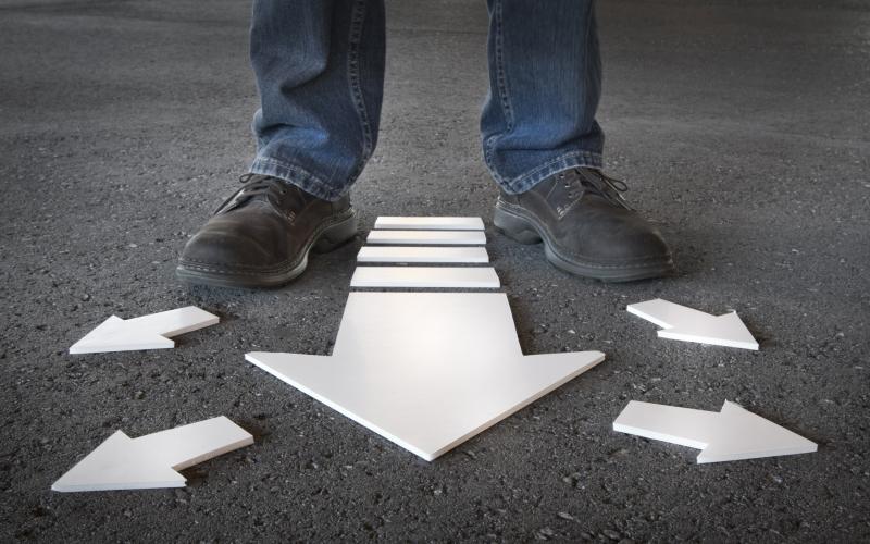 Person walking with arrows on pavement pointing in multiple directions